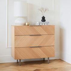 a wooden dresser with two drawers and a white lamp on top of it in a room