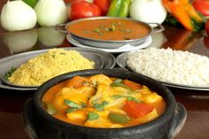 several different types of food are on the table with rice and vegetables in bowls next to each other