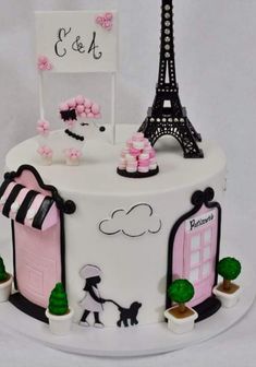 a white cake with pink and black decorations on it's sides, including the eiffel tower