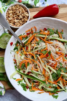 a salad with carrots, celery and nuts in a white bowl