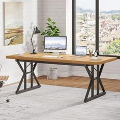 a computer desk with two laptops on it in front of a window overlooking the city