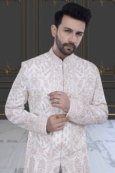 This impeccable sherwani, adorned with luxurious stones and intricate embroidery, exudes sophistication and elegance. Perfect for the stylish groom, it is a timeless masterpiece that will make a lasting impression. Indulge in the opulence and elevate your wedding day look with this R14-S71 sherwani. Off White Nehru Jacket With Naqshi For Wedding, Ceremonial Off White Bandhgala With Intricate Embroidery, Ceremonial Off-white Bandhgala With Intricate Embroidery, Elegant White Nehru Jacket With Traditional Drape, Elegant Cream Nehru Jacket For Designer Wear, Elegant Sherwani For Reception With Traditional Drape, Unstitched Off White Bandhgala With Long Sleeves, Elegant Designer Wear Off White Bandhgala, Elegant Designer Off White Bandhgala