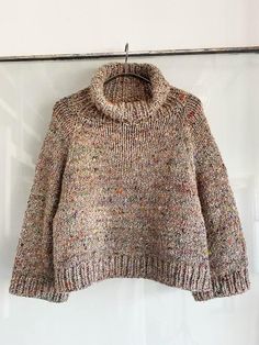 a sweater hanging on a hanger in front of a white wall