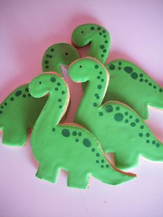 decorated cookies in the shape of dinosaurs on a pink surface