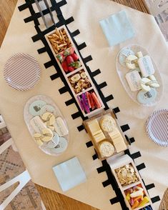 an assortment of cheeses, crackers, and fruit on a train track table