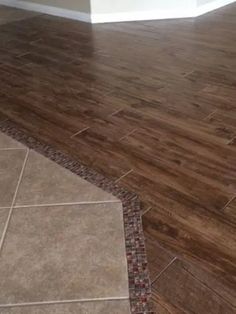 an empty room with wood flooring and tile on the ground in front of it