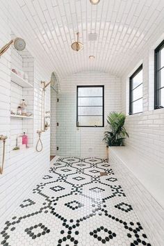 a bathroom with black and white tiles on the floor, windows, and shower head