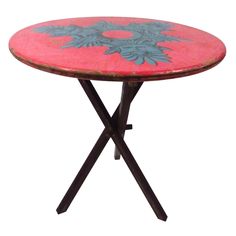 a pink and blue table sitting on top of a black metal stand with flowers painted on it