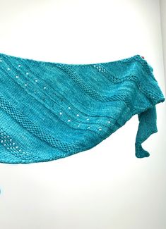 a blue knitted shawl hanging from a hook