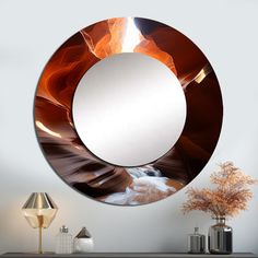 a round mirror hanging on the side of a wall next to a vase and lamp