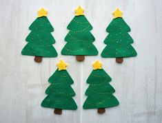 four felt christmas trees with yellow stars on them are arranged in the shape of small trees