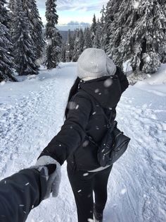 two people walking in the snow with their arms around each other's back, holding hands