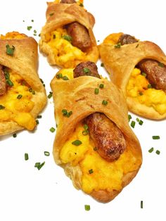 four sausage and egg breakfast rolls on a white plate with chives sprinkled around them