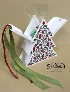 an origami christmas tree with ribbon tied around it and packaging on the side