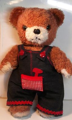 a brown teddy bear wearing black overalls and a red number one on it's chest