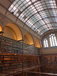 the inside of a large library with many bookshelves and arched ceiling lights above