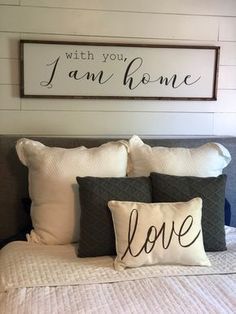 a bed with two pillows and a sign above it that says, with you i am home