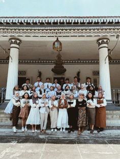 a group of people posing for a photo in front of a building with columns and pillars