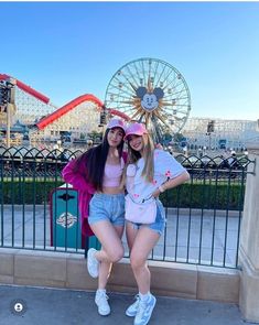 two girls standing next to each other in front of a ferris wheel at an amusement park