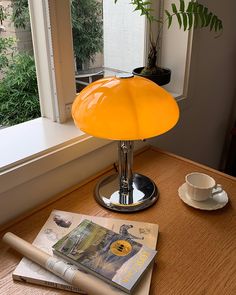 a yellow lamp sitting on top of a table next to a cup and saucer