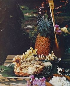 a pineapple sitting on top of a wooden table next to flowers and other items