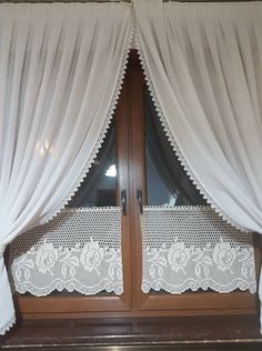 an open window with white curtains and lace