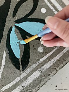 someone is using a pencil to draw a flower on the sidewalk with chalk and paint