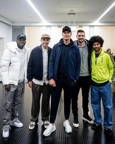 four men are posing for a photo in an office building with their arms around each other