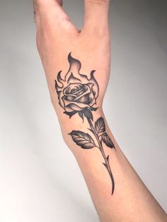 a person's hand with a rose tattoo on the left side of their arm