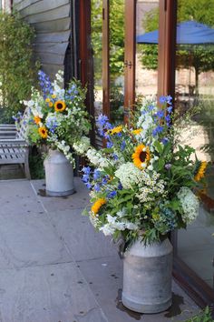 three vases with flowers are sitting on the sidewalk