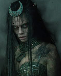 a woman with long hair and horns on her head, wearing an elaborate costume in the dark