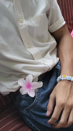 a man sitting on a couch wearing a bracelet with flowers attached to the clasps