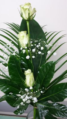 a vase filled with white flowers and greenery