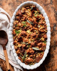 a casserole dish filled with meat and vegetables on top of a wooden table