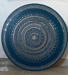 a blue plate with an intricate design on the front and back side, sitting on a tile floor