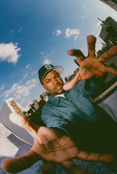 a man in a baseball cap making the peace sign with his hands while standing on top of a building