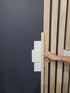 a person's hand is holding the door handle on a wooden paneled wall