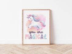 a unicorn poster with the words you are magic in front of it on a wooden floor