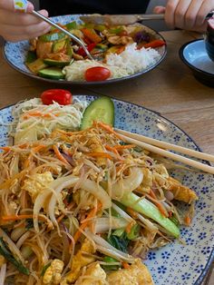 two plates of food with chopsticks on them, one has vegetables and the other has rice