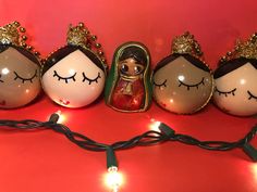 a group of christmas ornaments with eyes closed and lights around them on a red surface