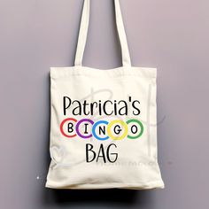 "This Personalized Bingo Tote Bag is the perfect gift for the Bingo lover in your family or to gift yourself.   Our canvas tote bags are perfect for everyday use.  These natural /off-white canvas bags are great for a variety of things, a quick trip to the grocery store for a few things, going to your local farmers market, carrying books, your laptop, shoes, clothes, and so much more.  100% Cotton, 12 oz heavy duty Canvas  Natural Color, off-white, beige Size - 15\" wide x 16\" high with 2 straps These totes are reusable and eco-friendly Each tote bag is hand-pressed with a heat press and either DTF (direct to film) and/or HTV (heat transfer vinyl).  Care instructions are included with each tote bag.  This product allows you to customize the name on the tote bag.  Please enter the NAME you' Local Farmers Market, Canvas Bags, Transfer Vinyl, White Canvas, White Beige, Heat Transfer Vinyl, Grocery Store, Farmers Market, Canvas Bag