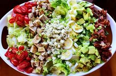 a large salad with tomatoes, lettuce and other vegetables in it on a white plate