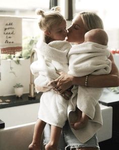 a woman is holding a baby wrapped in a towel and kissing her face with both hands