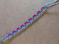 a blue and pink braided bracelet laying on top of a table