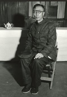 an old photo of a man sitting on a chair in front of a tea pot