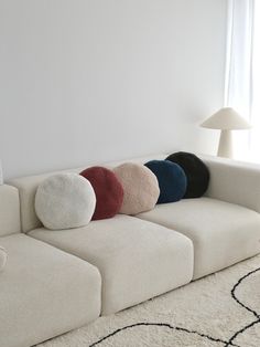 a living room with a white couch and four pillows on the back of it's seat