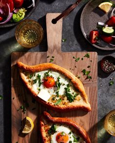 two slices of pizza on a cutting board topped with eggs and cheese, garnished with parsley