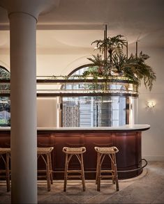 three stools are sitting at the bar in front of an arched window and potted plant