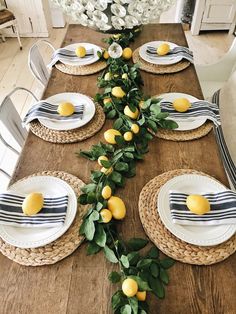 the table is set with lemons and greenery on it, along with place settings