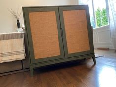 a green cabinet sitting on top of a hard wood floor next to a white wall